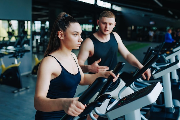 Un allenatore di fitness dedicato che istruisce un giovane uomo e una giovane donna durante una sessione di allenamento dinamico in una palestra ben attrezzata che promuove uno stile di vita sano e attivo