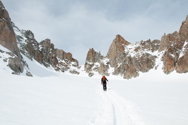 Un alpinista solitario che sale nella neve attraverso il ghiacciaio Saleina fino al passo Fenetre de Saleina nelle Alpi