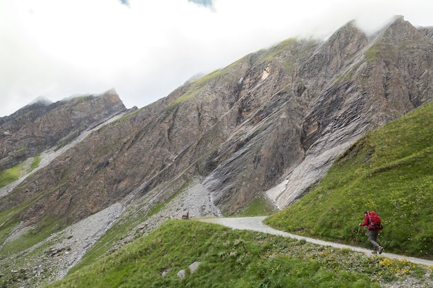 Un alpinista su una strada circondata da montagne rocciose nella nebbia nelle Alpi austriache vicino al vertice di roccia del Grossglockner Kals am Grossglockner Austria