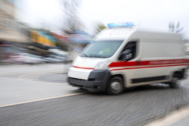 Un'ambulanza che risponde a una chiamata di emergenza guida veloce su strada in motion blur. Immagine sfocata. Concetto di assistenza sanitaria