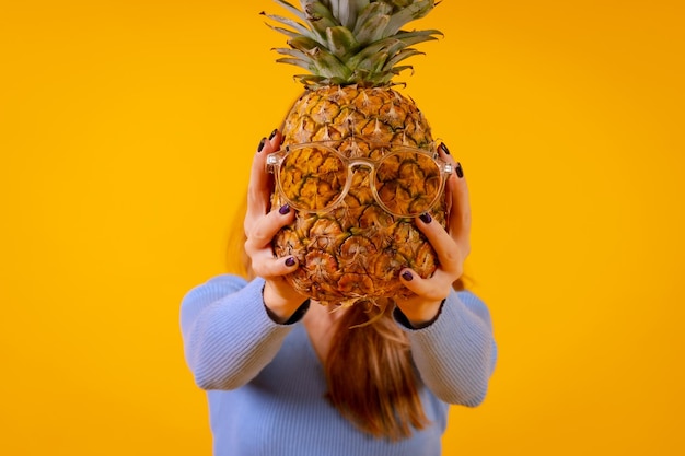 Un ananas in occhiali da sole in uno studio su sfondo giallo estate sana