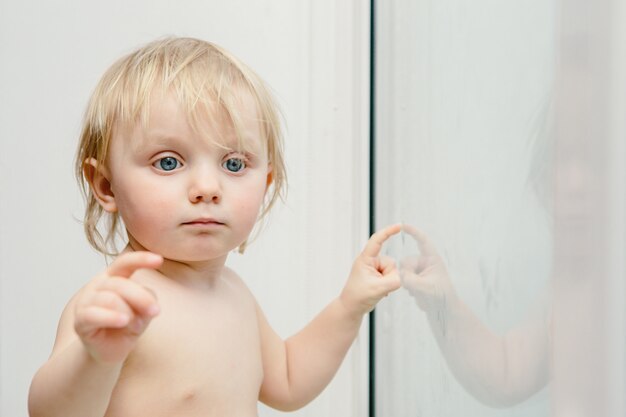 Un anno ragazza nella stanza. Piccolo bambino vicino alla finestra