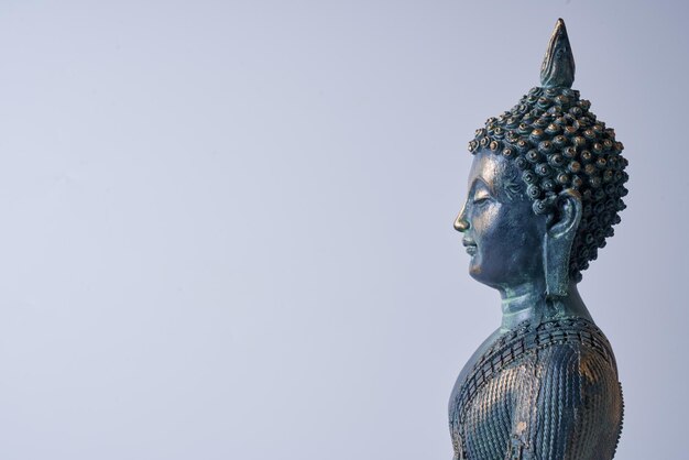 Un'antica statua di Buddha in bronzo su sfondo bianco isolato.