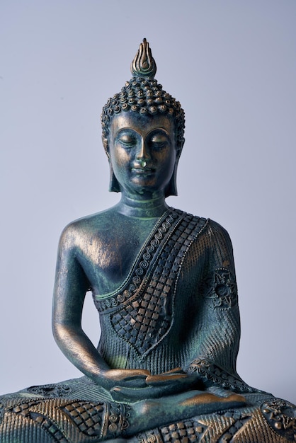 Un'antica statua di Buddha in bronzo su sfondo bianco isolato.