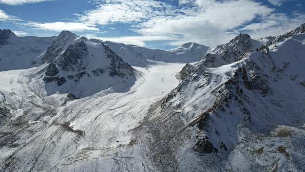 Un antico ghiacciaio di neve tra alte montagne. In alcuni punti ci sono ripide scogliere e grandi rocce.