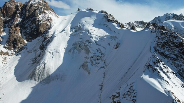 Un antico ghiacciaio di neve tra alte montagne. In alcuni punti ci sono ripide scogliere e grandi rocce.