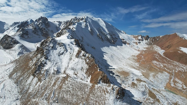 Un antico ghiacciaio di neve tra alte montagne. In alcuni punti ci sono ripide scogliere e grandi rocce.