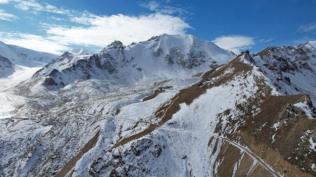 Un antico ghiacciaio di neve tra alte montagne. In alcuni punti ci sono ripide scogliere e grandi rocce.