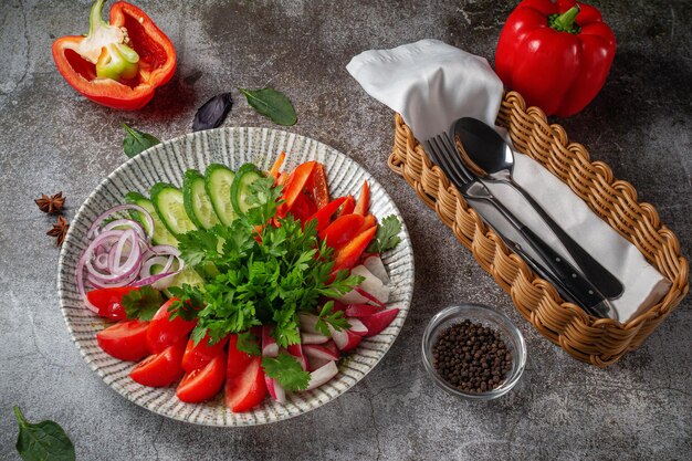 Un antipasto in un ristorante, verdure assortite. Verdure affettate a strati su un piatto con verdure contro un tavolo di pietra grigia