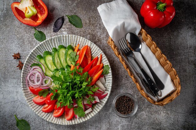 Un antipasto in un ristorante, verdure assortite. Verdure affettate a strati su un piatto con verdure contro un tavolo di pietra grigia