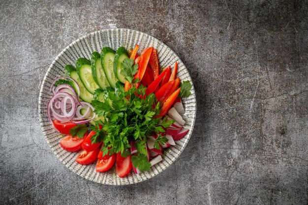 Un antipasto in un ristorante, verdure assortite. Verdure affettate a strati su un piatto con verdure contro un tavolo di pietra grigia