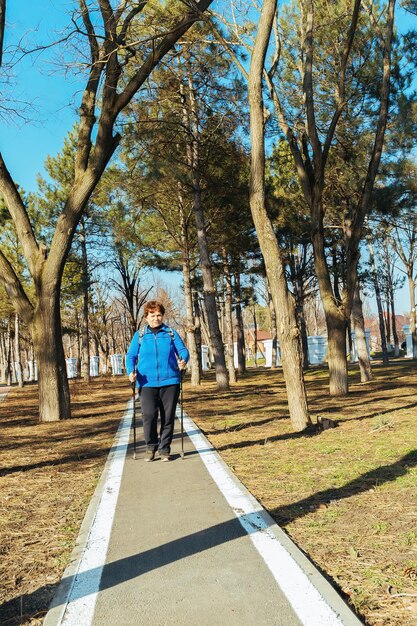 un'anziana donna attiva cammina nel parco su bastoncini scandinavi Stile di vita sano delle donne adulte