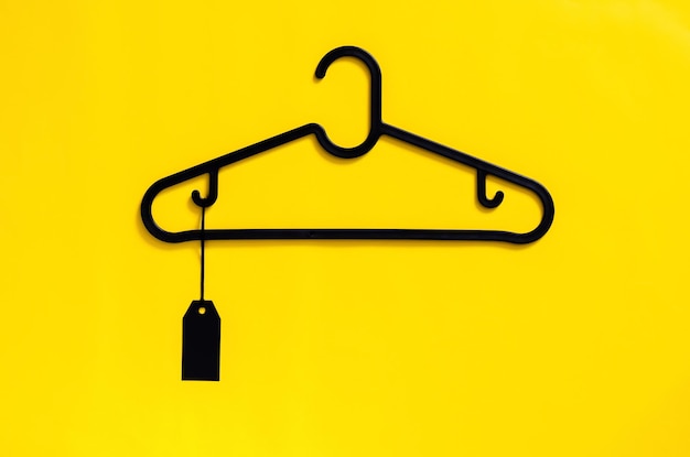 Un appendiabiti nero con etichetta di prezzo nera vuota su sfondo giallo concetto di venerdì nero
