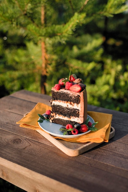 Un appetitoso pezzo di torta decorato con frutti di bosco si trova su un tavolo di legno in natura