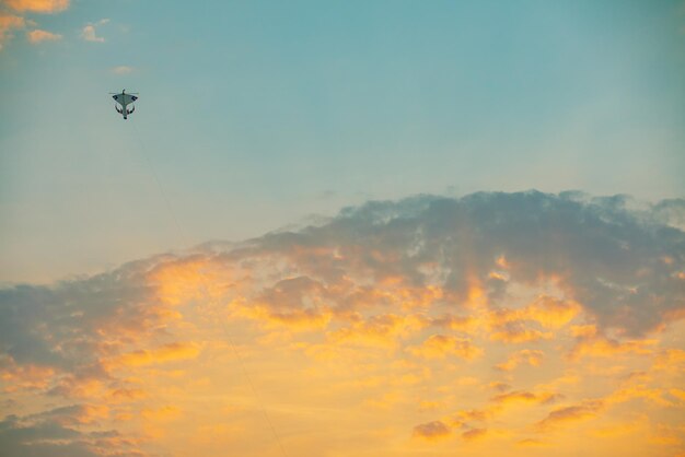 Un aquilone colorato al tramonto nel cielo con nuvole soffici e arancione