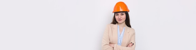 Un architetto ragazza in un vestito e un casco da costruzione arancione si trova su uno sfondo bianco