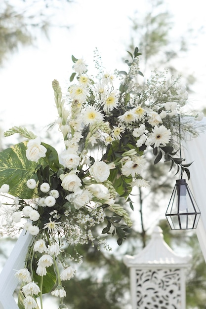 Un arco bianco con fiori e una lanterna appesa