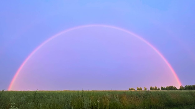 Un arcobaleno pieno dal tetto della casa sopra la foresta e le case Double Rainbow