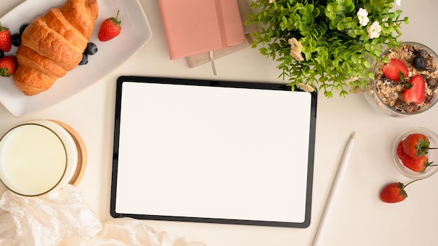 Un'area di lavoro con lo schermo bianco del computer tablet digitale e una sana colazione vista dall'alto