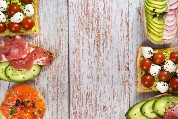 Un assortimento di panini con pesce, formaggio, carne e verdure giace sul tavolo di legno