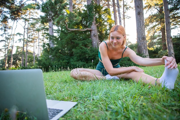 Un'atleta esegue esercizi di allungamento dopo le lezioni online con il suo laptop