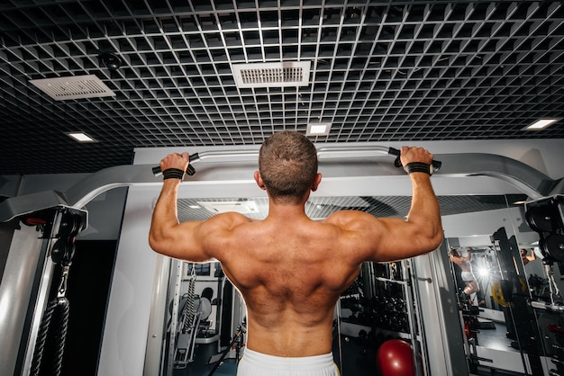 Un atleta esegue pull-UPS in palestra. Fitness, bodybuilding.