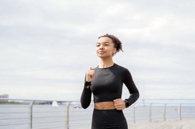 Un'atleta femminile che esegue esercizi di cardio fitness utilizza un orologio fitness e un tracker per misurare il battito cardiaco