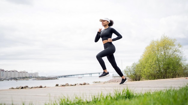 Un'atleta femminile corre fa un allenamento per strada in abbigliamento sportivo e un orologio fitness in mano