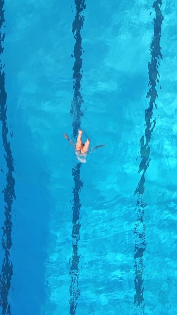 Un'atleta femminile esegue routine di nuoto sincronizzate in una piscina all'aperto vista dall'aria