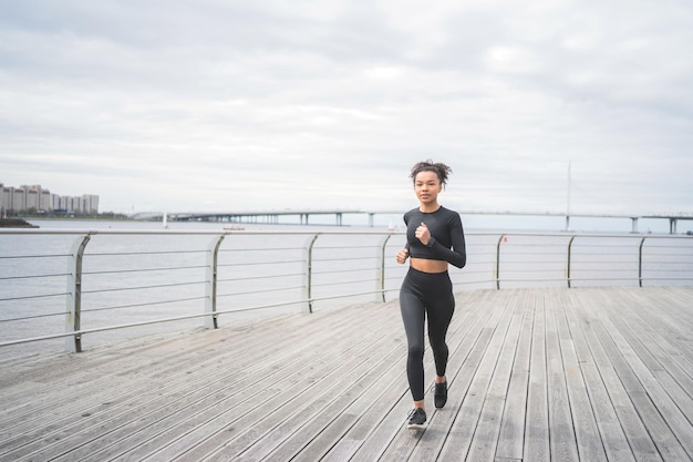 Un'atleta femminile fa esercizi di cardio fitness utilizza un orologio fitness e un tracker per misurare