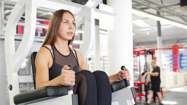 Un atleta in forma donna che si allena in palestra eseguendo una gamba che esercita un apparato di allenamento