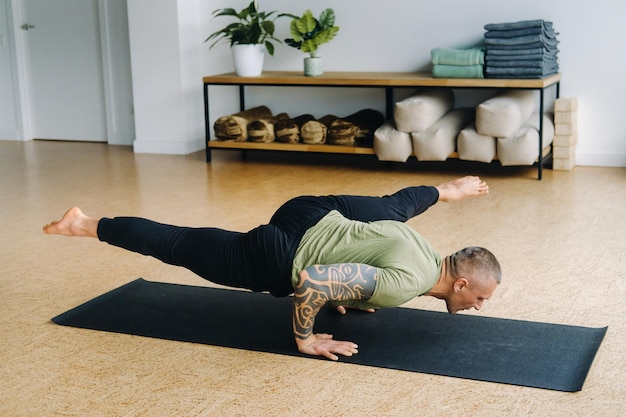 Un atleta maschio con una maglietta verde fa yoga in palestra