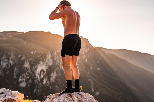 Un atleta riposa in cima a una montagna dopo un estenuante allenamento di corsa