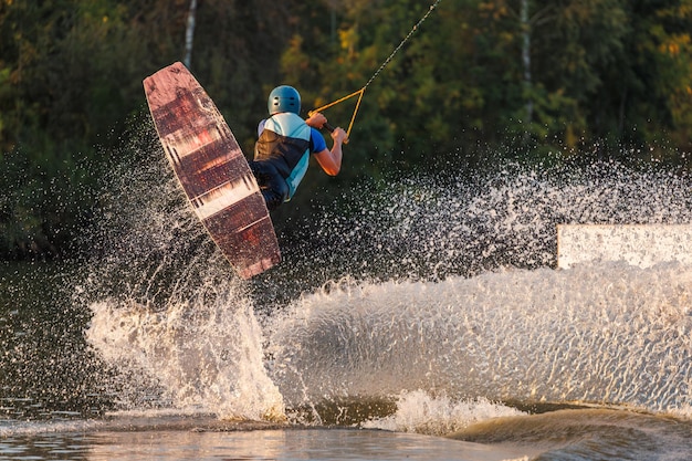 Un atleta salta da un trampolino Wakeboard park al tramonto Un uomo esegue un trucco su una tavola