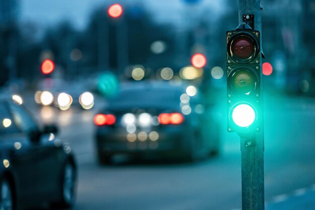 Un attraversamento della città con un semaforo su uno sfondo sfocato con le macchine nelle strade serali luce verde