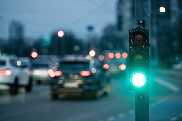 Un attraversamento della città con un semaforo su uno sfondo sfocato con le macchine nelle strade serali luce verde