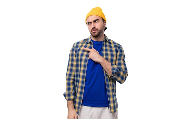 Un autentico giovane uomo brunetto europeo con barba e baffi brutali vestito con cappello giallo e blu