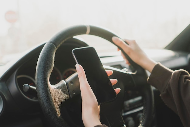 Un'autista disattenta che utilizza lo smarphone sul sedile del conducente dell'auto