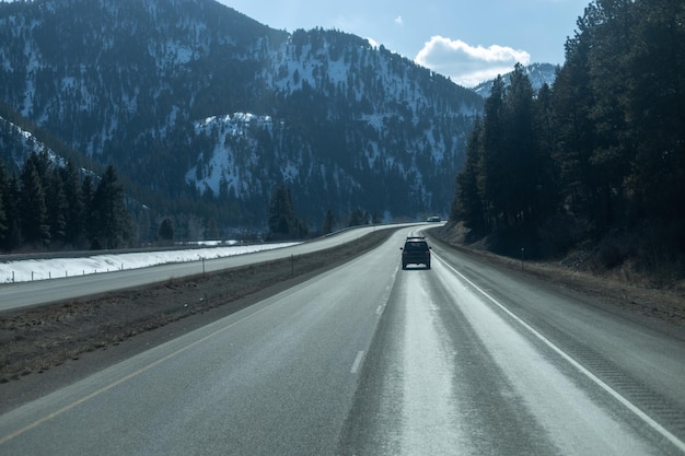 Un'auto che guida su un'autostrada con le montagne sullo sfondo