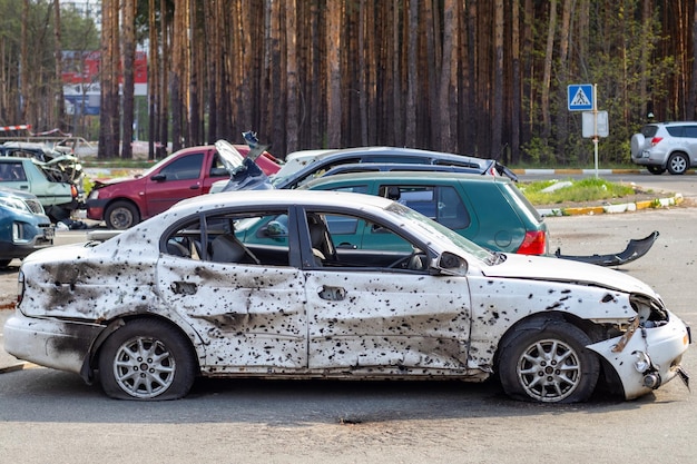 Un'auto distrutta dalle schegge di un razzo esploso vicino al cimitero di automobili di Irpensky Conseguenze dell'invasione dell'esercito russo in Ucraina Veicolo civile distrutto