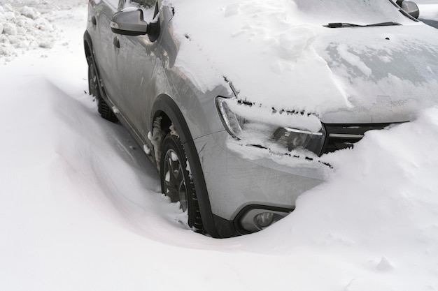 Un'auto parcheggiata in un parcheggio è coperta di neve e non è in grado di guidare
