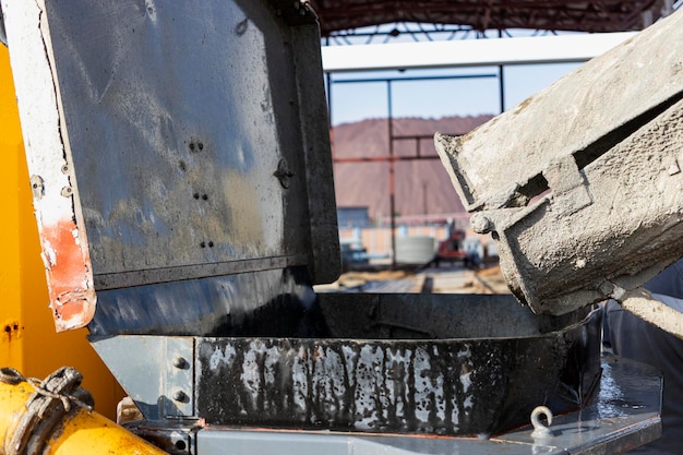 Un'autobetoniera versa la malta in una pompa per calcestruzzo in un cantiere edile. Fornitura di calcestruzzo e malta per la produzione di opere monolitiche in cemento armato. Avvicinamento.