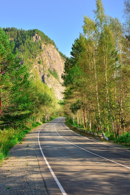 Un'autostrada vuota tra betulle e scogliere di montagna Khakassia Siberia Russia