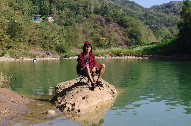 Un avventuriero che si riposa vicino al fiume con l'acqua verde e bella