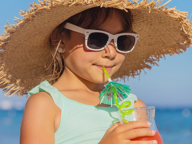 Un bambino al mare beve un cocktail.