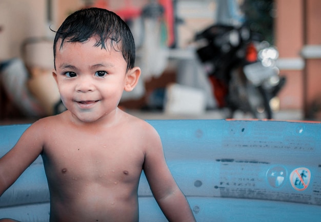 Un bambino allegro gioca nella piscina per bambini gonfiabile blu.