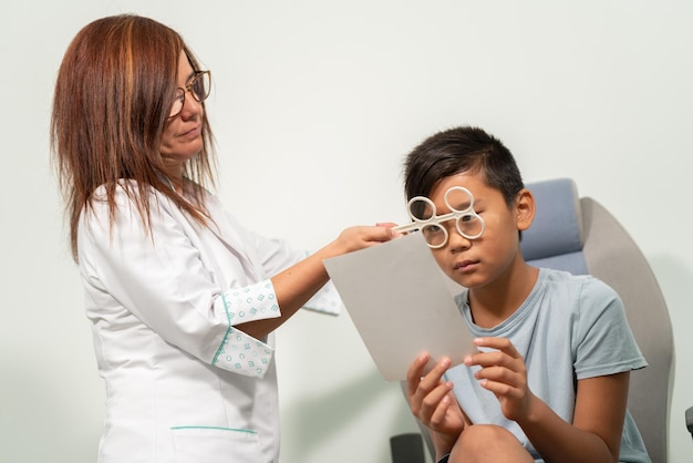 Un bambino asiatico con una donna optometrista caucasica che esamina da vicino la vista in una consultazione