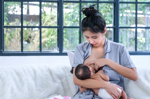 Un bambino asiatico di 2 mesi è felice di succhiare il latte materno.