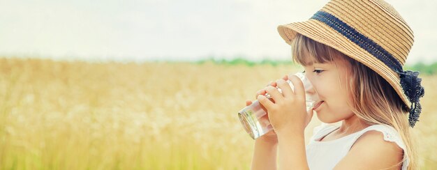 Un bambino beve acqua sullo sfondo del campo.