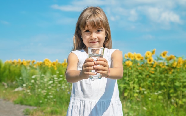 Un bambino beve acqua sullo sfondo del campo